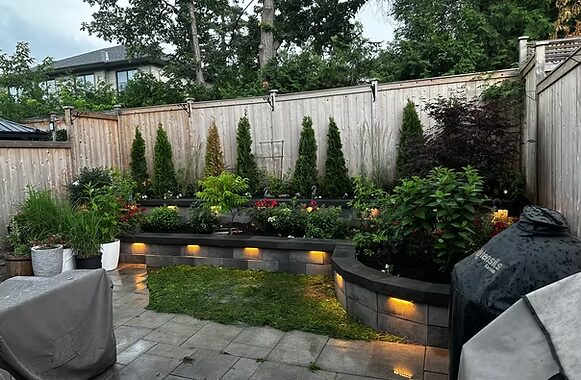 Raised stone garden beds with built-in lighting at dusk