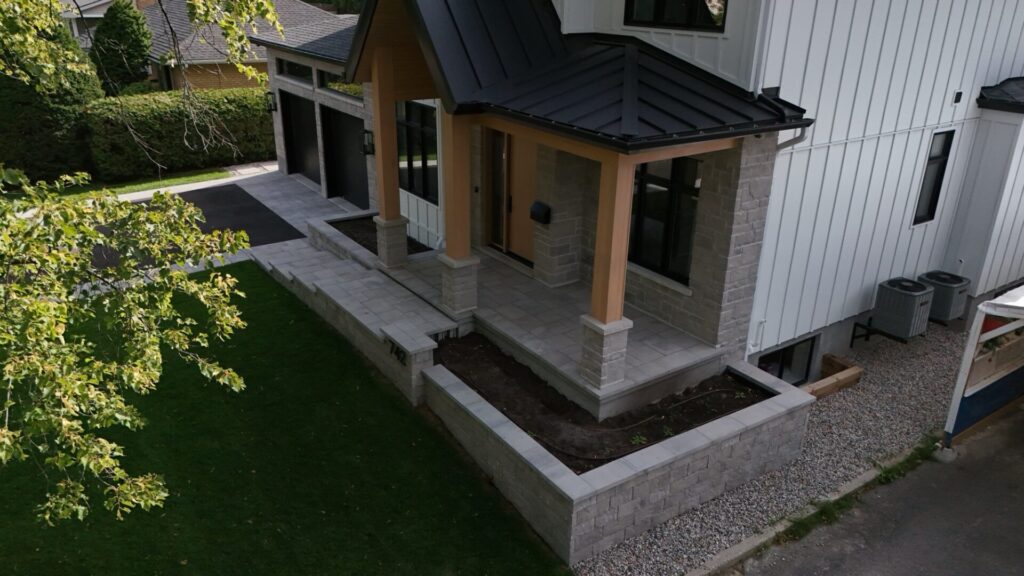 Covered front porch with a stone planter wall and new sod, seen from above